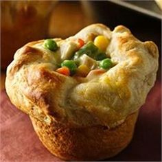 a close up of a muffin on a plate with peas and carrots in it