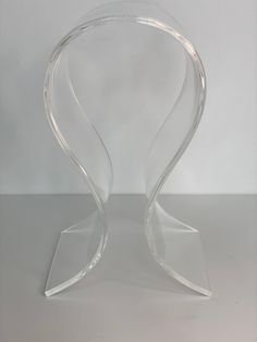 an acrylic chair with curved legs on a white surface, in the shape of a heart