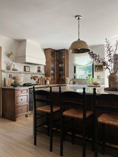 a kitchen with an island and wooden chairs in the center, surrounded by wood flooring