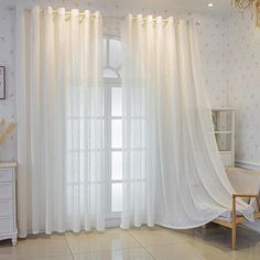 a living room with white furniture and curtains