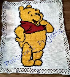 a crocheted winnie the pooh pillow on top of a wooden table next to a white doily