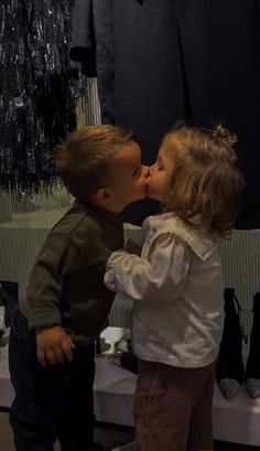 two small children are kissing each other in front of a mannequin's dummy