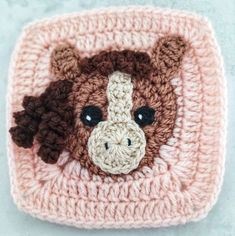 a crocheted square with a brown and white cow on it's face