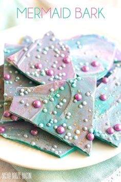 purple and blue decorated cookies on a plate with the words mermaid bark written above them