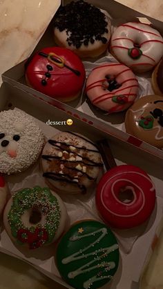 two boxes filled with assorted decorated donuts on top of a marble countertop