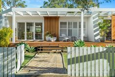 a small white house with a wooden deck in the front yard and covered patio area