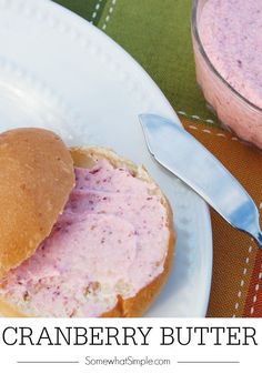 a plate with a sandwich on it next to a jar of strawberry butter and a spoon