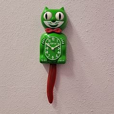 a green clock with a cat face on it's face is hanging from the wall