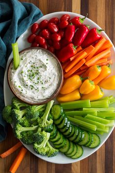 a white plate topped with veggies and dip surrounded by carrots, broccoli