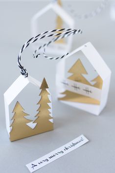 two origami christmas trees with tags attached to the top and one hanging on a string