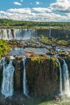 a boat is in the water near a large waterfall that has many falls on it