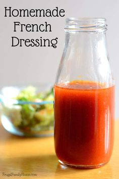 homemade french dressing in a glass jar on a wooden table with salad in the background