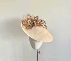 A simple yet striking cream and gold sweeping brim headpiece. Perfect for Royal Ascot, mother of the bride, or Ladies Day. Made from sinamay straw in a beautiful shade of deep coffee cream, it features a structural arrangement of sinamay loops in shades of gold, ivory and deep cream.  This headpiece measures 14 inches and is with a metal headband that would be wrapped in a colour ribbon to blend in with your own hair colour.  A beautiful; and elegant choice if you are wanting something simple ye Elegant Gold Top Hat For Royal Ascot, Elegant Hat With Round Crown For Kentucky Derby, Elegant Gold Adjustable Boater Hat, Gold Top Hat For Wedding At Royal Ascot, Gold Top Hat For Wedding And Royal Ascot, Elegant Gold Wide Brim Boater Hat, Elegant Mini Hats With Round Crown For Spring, Elegant Gold Boater Hat With Curved Brim, Elegant Adjustable Gold Boater Hat