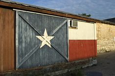 an old building with a texas flag painted on it's side in front of a brick wall