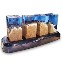 four wooden blocks sitting on top of a metal stand with blue glass cubes in them