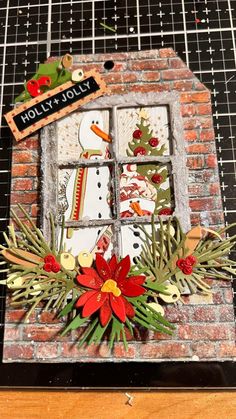 a christmas card with a snowman in the window and holly wreaths on it