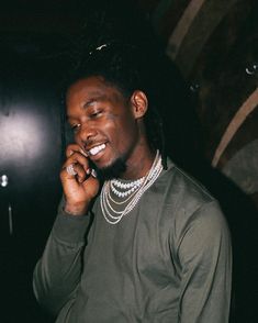 a man with dreadlocks talking on a cell phone in a dark room at night