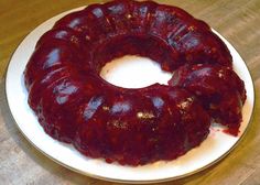 a bundt cake on a white plate sitting on a wooden table next to a knife and fork