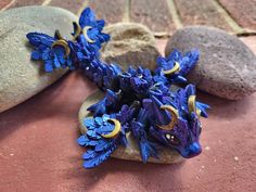 a purple and blue brooch sitting on top of some rocks