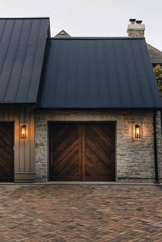 two brown garage doors are open in front of a brick building with black shingles