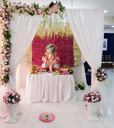 a decorated stage with flowers and an idol in the middle, surrounded by white drapes