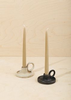 two small candlesticks sitting next to each other on top of a wooden table