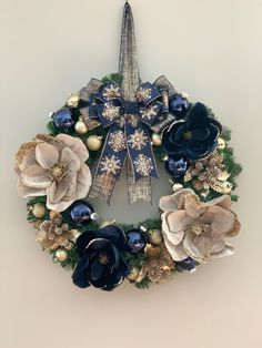 a christmas wreath with blue and gold flowers on the front, hanging from a wall