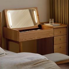 a wooden desk with a mirror on it in a bedroom next to a bed and window