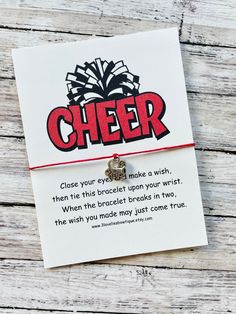 a card with the words cheer written on it and a small charm attached to it