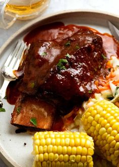 a white plate topped with meat, corn and coleslaw