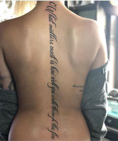 the back of a woman's upper body with writing on her left arm and lower back