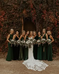 a group of women standing next to each other in front of a wall covered with ivy