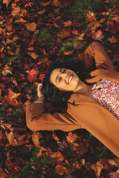 a woman laying on the ground surrounded by leaves