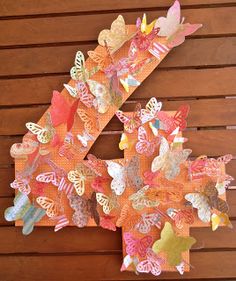 the letter k is made out of colorful paper butterflies on a wooden background with wood slats