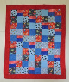 a blue and red patchwork quilt hanging on a wall