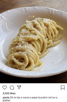 a white plate topped with pasta on top of a wooden table