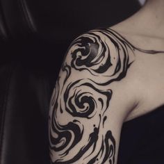 a woman's arm with black and white swirls tattooed on her left arm