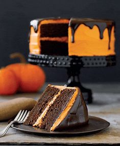 a slice of chocolate cake on a plate with a fork and pumpkins in the background