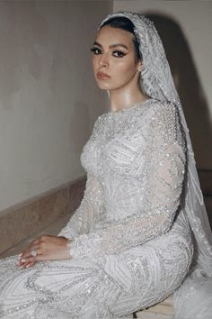 a woman in a white wedding dress sitting on the floor wearing a veil and tiara