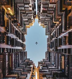 an airplane is flying through the air between buildings