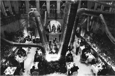 an overhead view of people eating at tables in a large room with exposed pipes on the ceiling