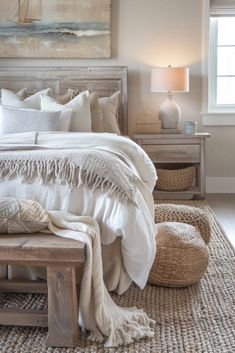 a bed with white linens and pillows in a bedroom next to a painting on the wall