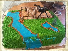 a cake that is shaped like a farm scene with horses and a river running through it