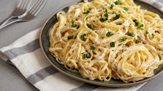 a plate full of pasta with parsley on the side and a fork next to it