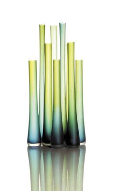 green and blue vases are stacked on top of each other in front of a white background