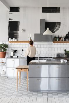 a woman standing at the counter in a kitchen