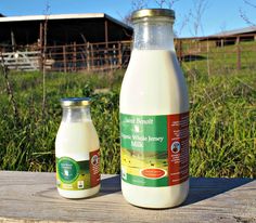 two bottles of milk sitting on top of a wooden table