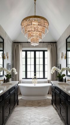 a bathroom with a tub, chandelier and two sinks in front of a large window