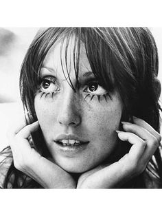 a black and white photo of a woman with freckles on her face looking at the camera