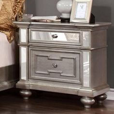 a silver nightstand sitting on top of a hard wood floor next to a white bed